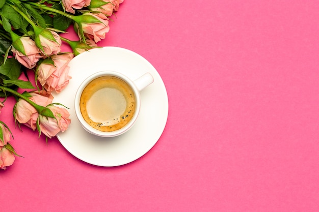 Rosas cor de rosa, xícara de café sobre fundo rosa brilhante