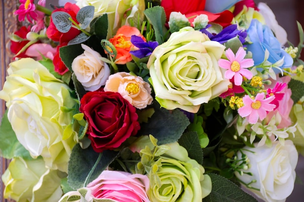 Rosas de plástico coloridas e outras flores para decoração e móveis no jardim ao ar livre