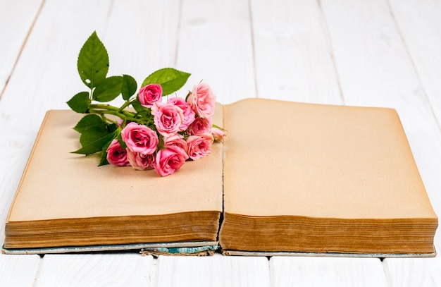 Rosas em um livro antigo sobre fundo branco de madeira. flores