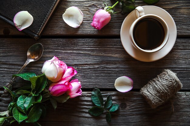 Rosas frescas com diário e café na mesa de madeira, vista superior. flores, bebida quente