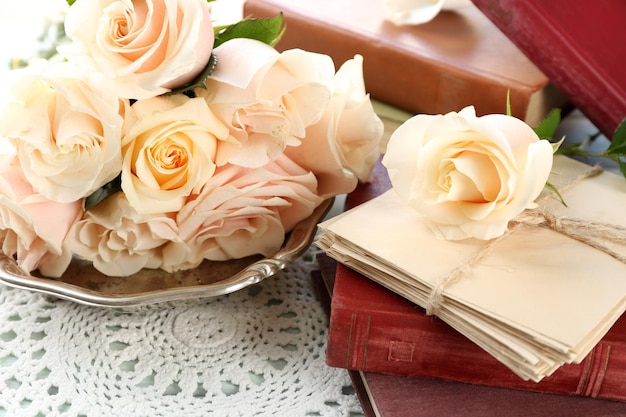 Rosas frescas com um livro velho e letras no fundo da mesa de madeira de cor. Conceito vintage