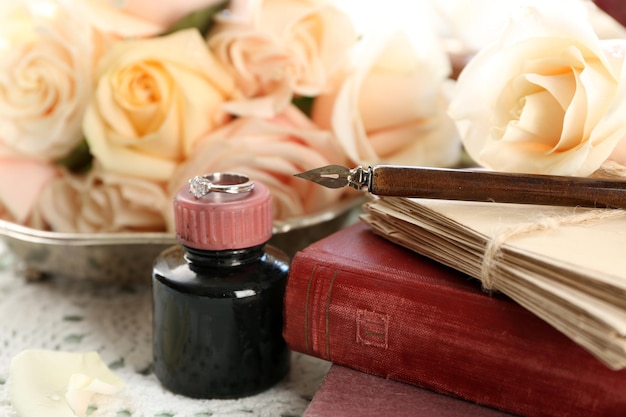 Foto rosas frescas com um livro velho e letras no fundo da mesa de madeira de cor. conceito vintage