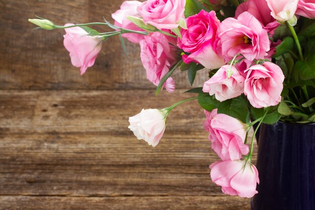 Rosas frescas e flores de eustoma na mesa de madeira