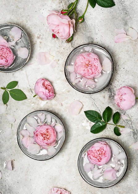 Rosas frescas e pétalas de rosa nas tigelas de água perfumada