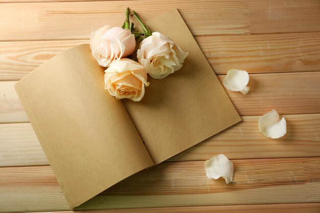 Rosas frescas en un viejo cuaderno, en el fondo de una mesa de madera