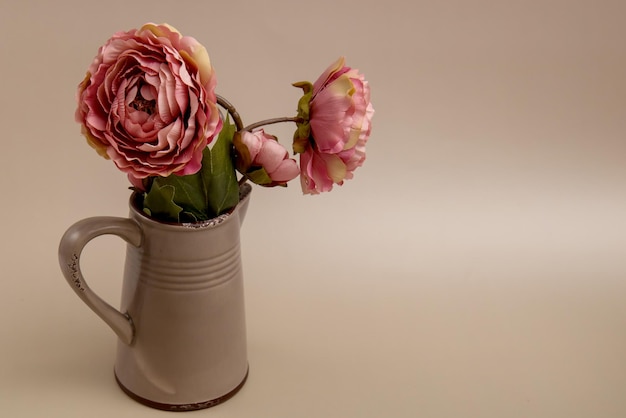 Rosas en una jarra de cerámica sobre un fondo beige con una tarjeta de felicitación con espacio para copiar