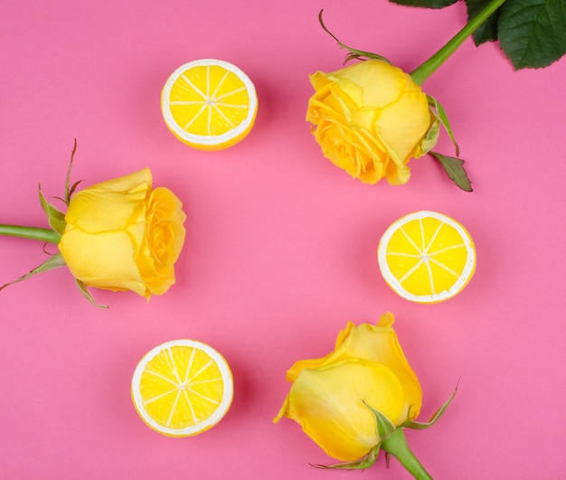 Rosas y limones sobre un fondo rosa