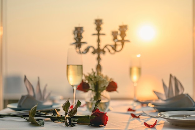 Rosas na mesa para o jantar dos namorados dos namorados Com taças de vinho e castiçais. Vistas do pôr do sol em edifícios altos. Dia dos namorados, casal, lua de mel, jantar, vinho, conceito romântico.