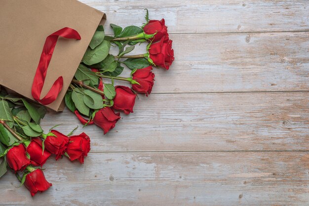 Rosas rojas en bolsa de compras artesanales una superficie de madera