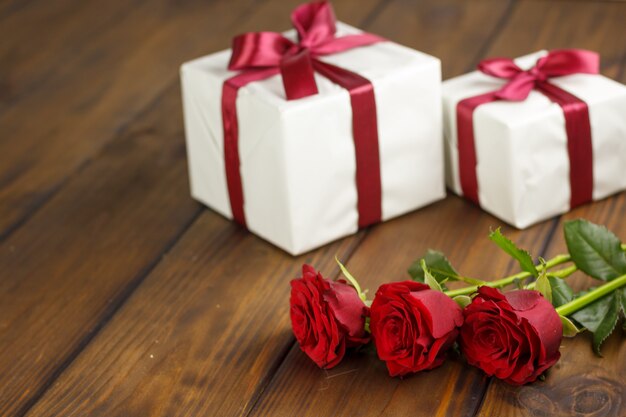 Rosas rojas y caja de regalo en mesa de madera marrón