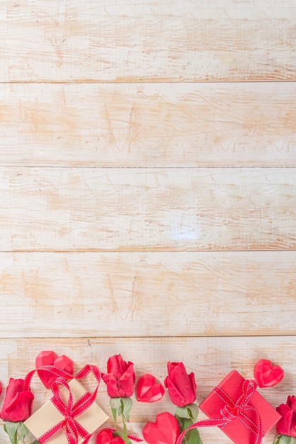 Rosas rojas y cajas de regalo y decoración de corazón en mesa de madera blanca. Vacaciones de San Valentín