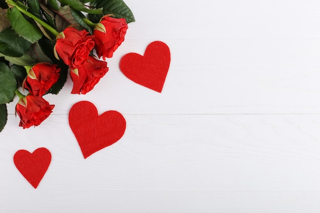 Rosas rojas y corazones en una mesa de madera blanca