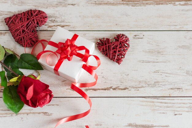 Rosas rojas con corazones y regalo en madera