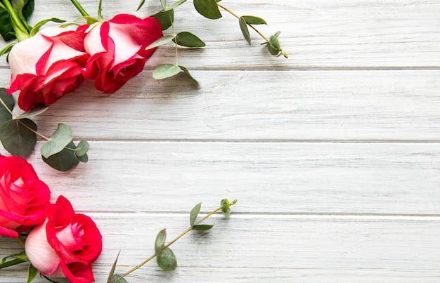 Rosas rojas con eucalipto sobre fondo de madera