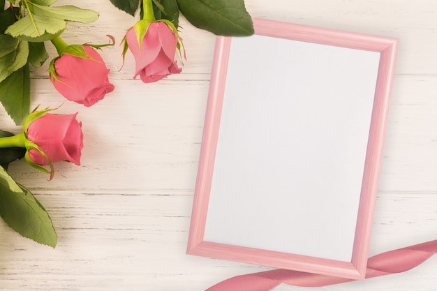 Foto rosas rojas y fondo de madera clara con marco rosa para el día de san valentín