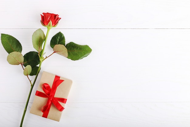 Rosas rojas, un regalo en una mesa de madera blanca