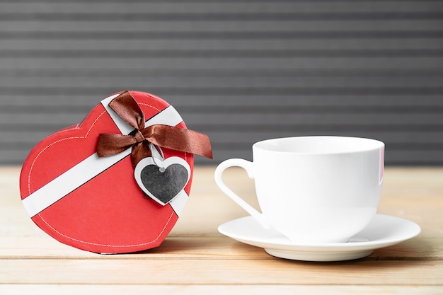 Rosas rojas y taza de café sobre fondo de madera