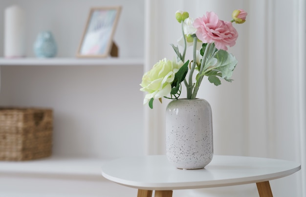 Rosas rosadas y amarillas en florero blanco moderno en mesa auxiliar blanca