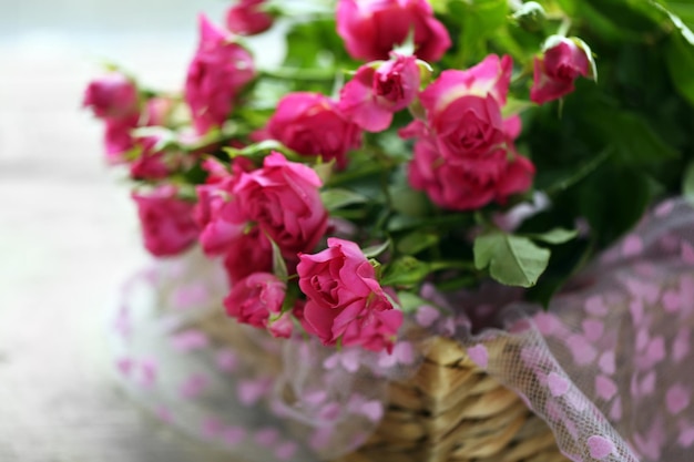 Rosas rosadas en una cesta de mimbre en una mesa de cerca