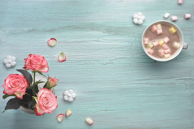 Rosas rosadas y chocolate caliente sobre menta clara con flores decorativas de cerámica