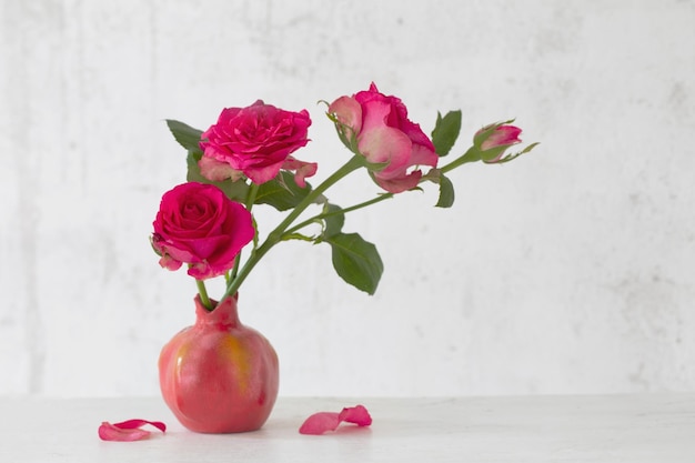 Foto rosas rosadas en jarrón rosa sobre fondo de pared blanca vieja