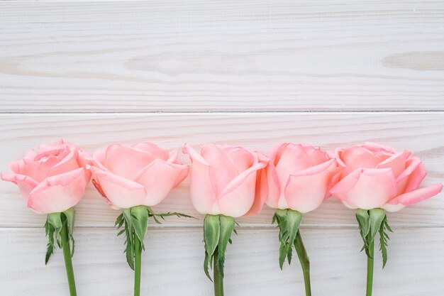 Rosas rosadas en una mesa de madera.