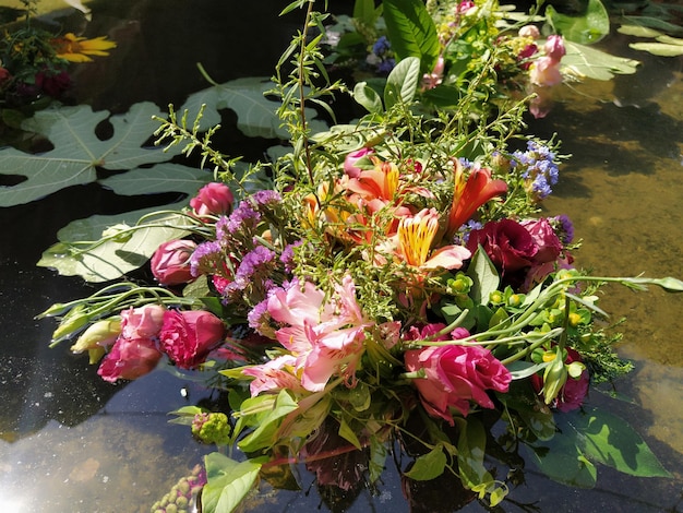 Rosas rosadas y rojas en un ramo flotando en el agua de un estanque Brotes arrancados como decoración para unas vacaciones de verano Ivan Kupala solsticio de verano Festival de la cosecha