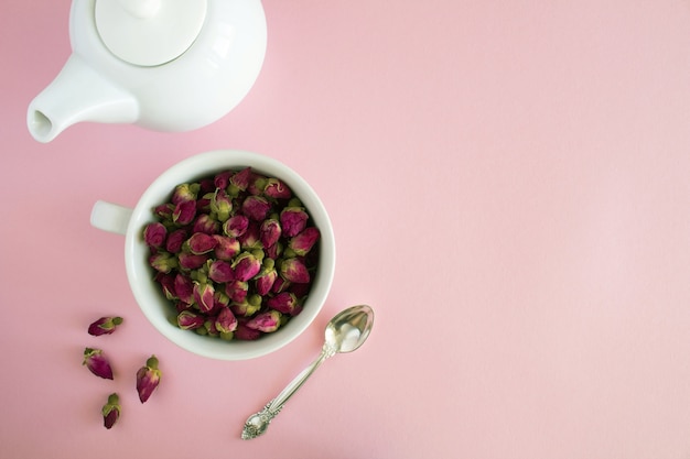 Rosas rosadas secas en la taza blanca y vista superior de la tetera