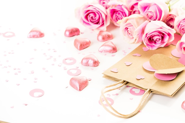 Rosas rosas y bolsa de regalo hecha a mano sobre un fondo blanco.