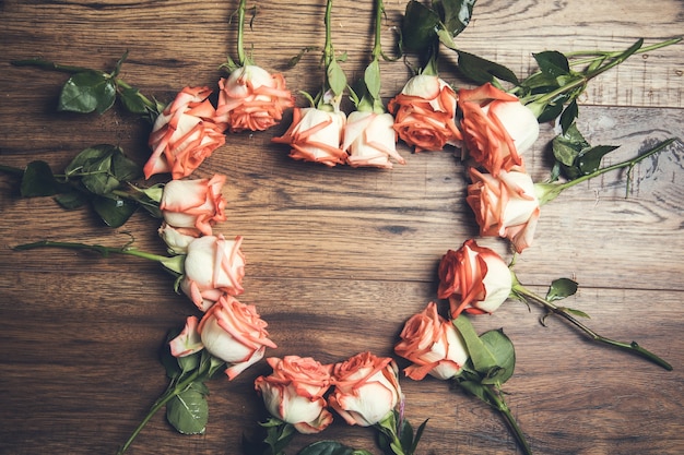 Rosas rosas y corazón en la mesa de madera