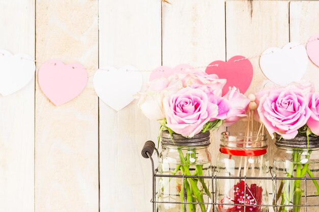 Foto rosas rosas en frascos en estante de madera rústica para el día de san valentín.