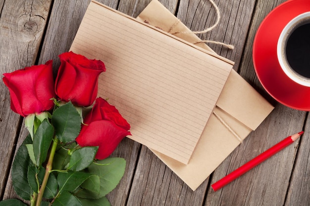 Rosas vermelhas do bloco de notas da carta de amor e xícara de café