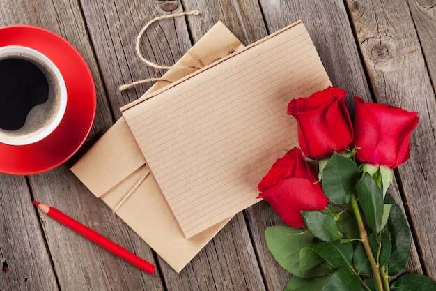 Rosas vermelhas do bloco de notas da carta de amor e xícara de café