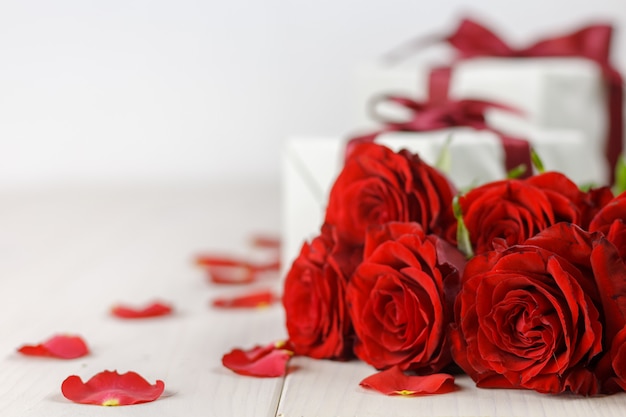 Rosas vermelhas e caixa de presente na mesa de madeira branca