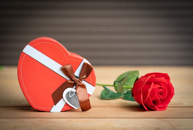 Rosas vermelhas e caixa em forma de coração no fundo madeira