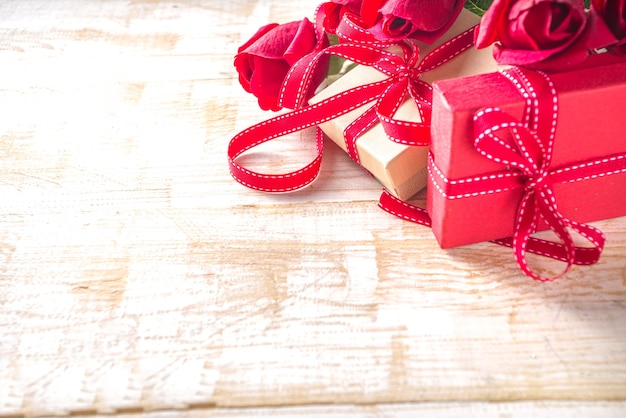 Rosas vermelhas e caixas de presente e decoração de coração na mesa de madeira branca. feriado do dia dos namorados