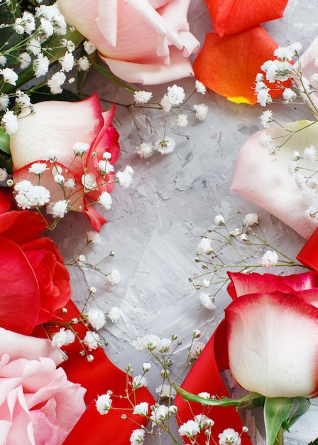 Foto rosas vermelhas e pequenas flores brancas com fita em um fundo cinza