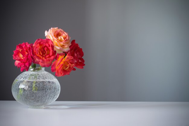 Rosas vermelhas em vaso de vidro em fundo cinza