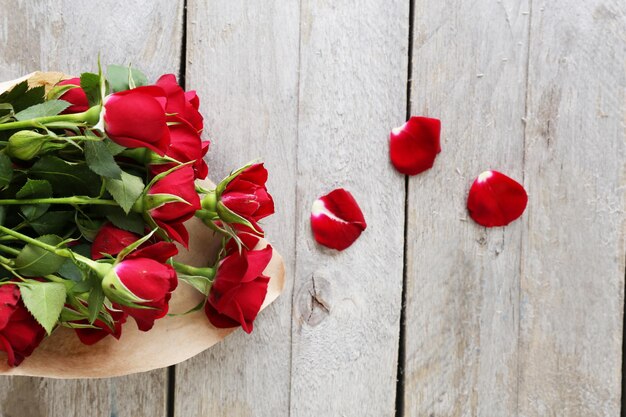 Rosas vermelhas embrulhadas em papel no fundo da mesa de madeira