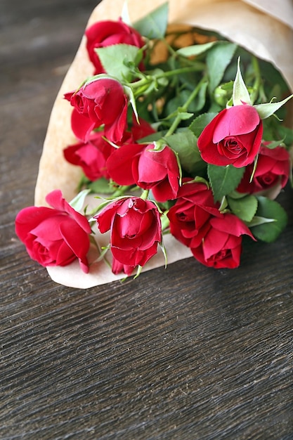 Rosas vermelhas embrulhadas em papel no fundo da mesa de madeira