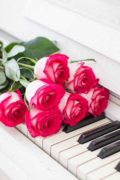 Rosas vermelhas luxuosas em um piano. buquê de rosas vermelhas e teclas de piano