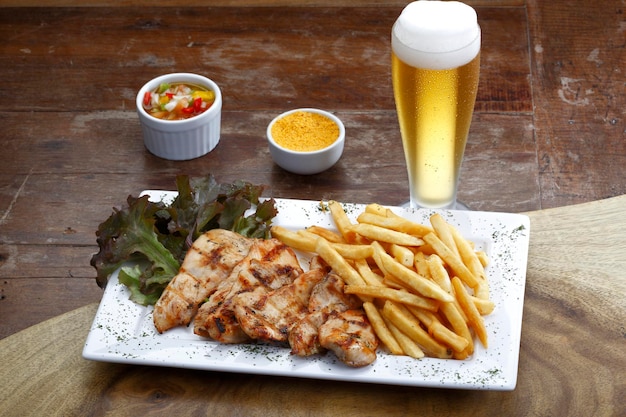 Rosbif con patatas y ensalada y un vaso de cerveza