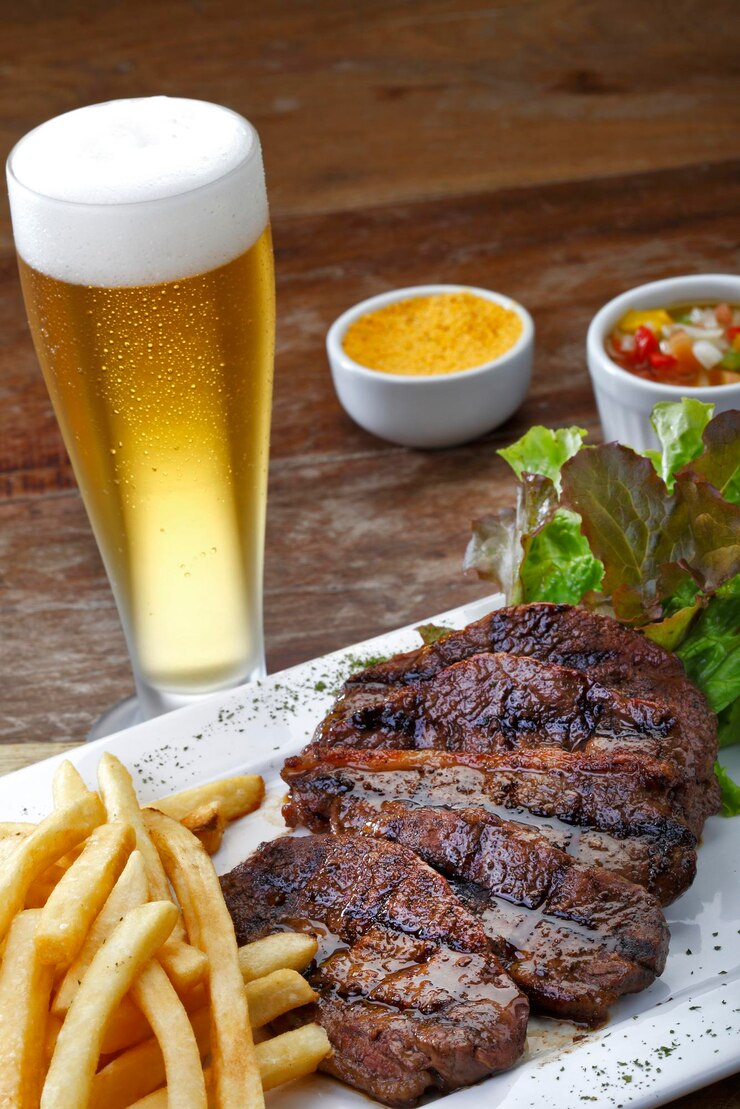 Foto rosbife com batata e salada e um copo de cerveja
