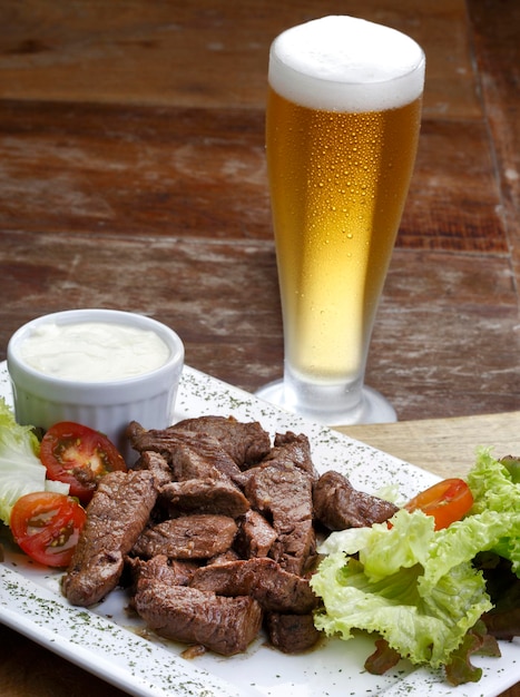 Foto rosbife com batata e salada e um copo de cerveja