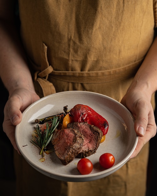 Rosbife com legumes no prato pendurado pelo chef