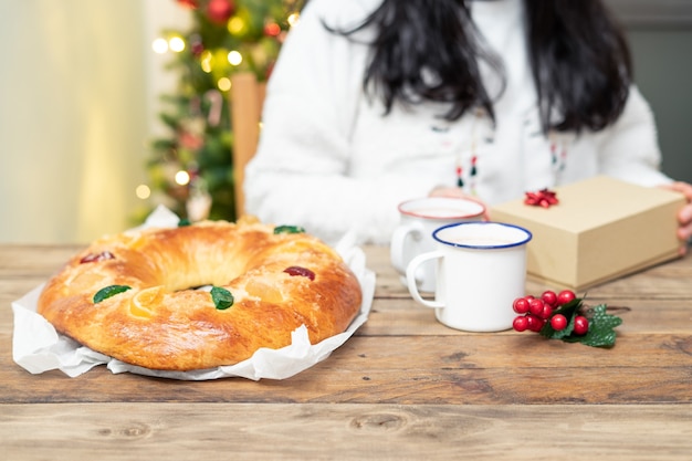 roscon de reyes (doce típico espanhol) inteiro na mesa de madeira com a árvore de Natal ao fundo. Doces de Natal.