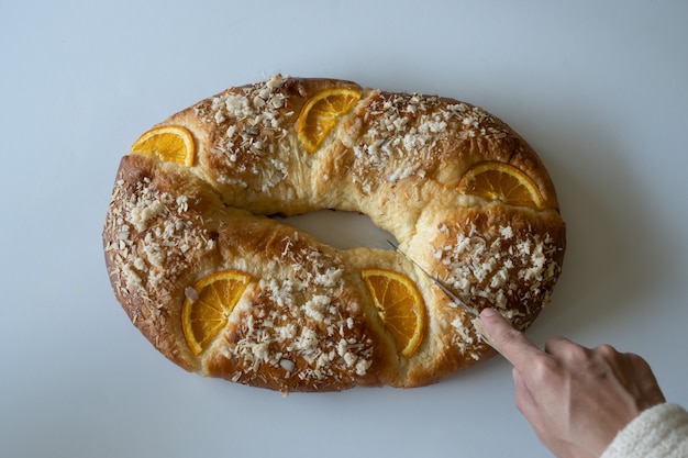 Roscón de Reyes se corta sobre un fondo blanco.