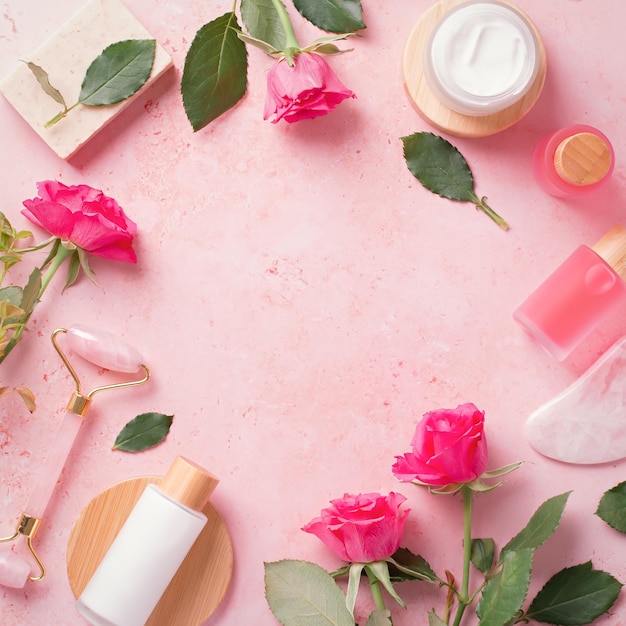 Rose extrair cosméticos naturais em garrafas reutilizáveis com rolo de beleza facial gua sha e flores rosas naturais em moldura quadrada rosa