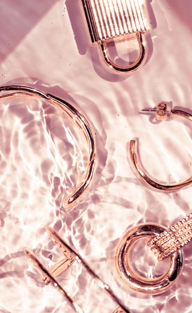 Roségold Armbänder Ohrringe Ringe Schmuck auf rosafarbenem Wasser Hintergrund Luxus Glamour und Urlaubsschönheitsdesign für Schmuckmarkenanzeigen