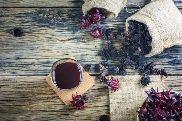 Roselle fresco, roselle secado y jugo de roselle en una tabla de madera.